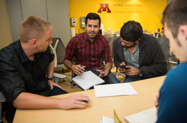 Photo of four MDI students huddled and brainstorming at the Medical Device Center