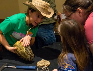 student showing a mammoth tooth to a youngster