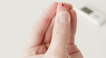 Hand with a blood drop on a finger from a finger prick