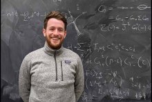 Andrew Hardy in front of blackboard with physics problem in chalk