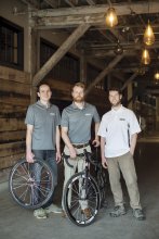 Three men standing in a renovated warehouse.