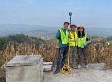 Three people pose with GPS pole technology in Guatemala