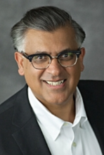A man wearing glasses and a sport coat smiling