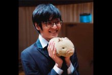 Yueh-Chen Lee headshot in suit holding stuffed animal pig