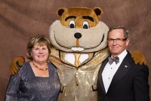 Ron and Janet Christenson posing with Goldy Gopher in a golden suit