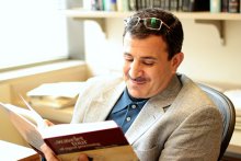 Emad Ebbini sitting in chair reading a book