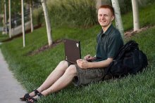 Max Shinn sitting in grass with laptop