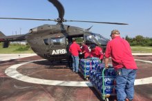 Four men loading supplies into a helicopter.
