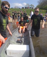 students guide concrete canoe into the water