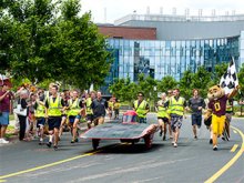 students jogging behind solar car