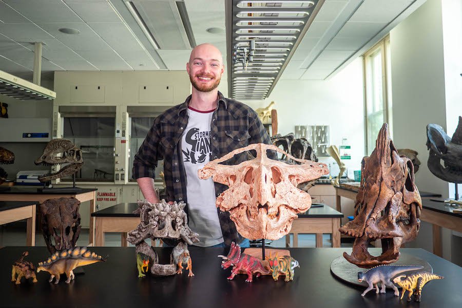 U of M CSE Ph.D. student Viktor Radermacher poses with dinosaur fossils in Tate Hall