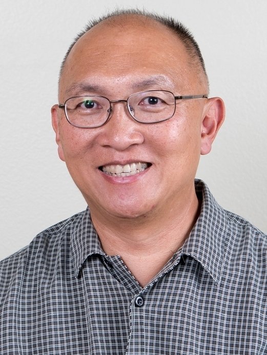 Alvin Loke in a black and white plaid shirt smiling into the camera