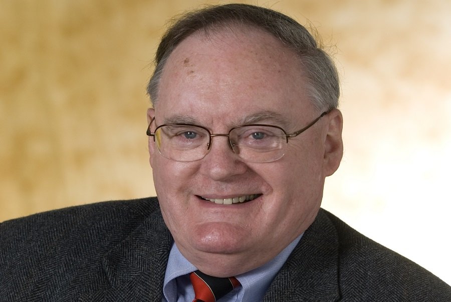 Professor Bruce Wollenberg in a dark suit smiling into camera