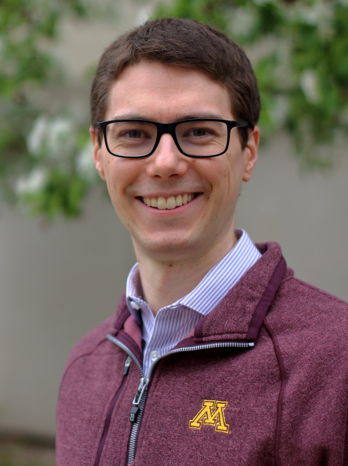 Professor Ryan Caverly smiling wearing a maroon UMN shirt