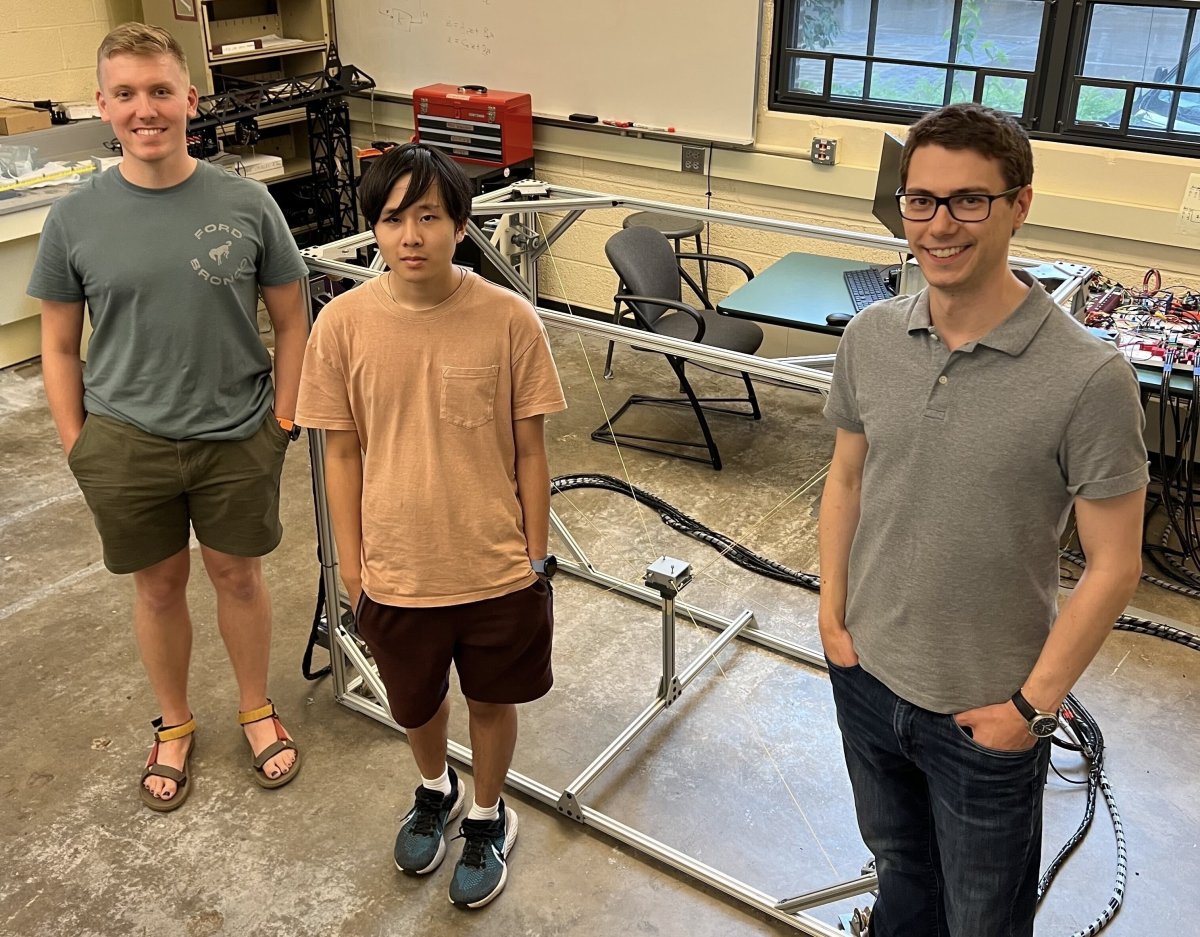 Keegan Bunker, Vinh Nguyen, and Prof. Caverly in front of a cable-driven parallel robot that was built by students in the Aerospace, Robotics, Dynamics, and Control (ARDC) Laboratory.