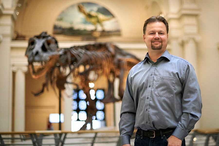 Peter Makovicky standing in front of Sue, dinosaur on display at the Field Museum in Chicago.