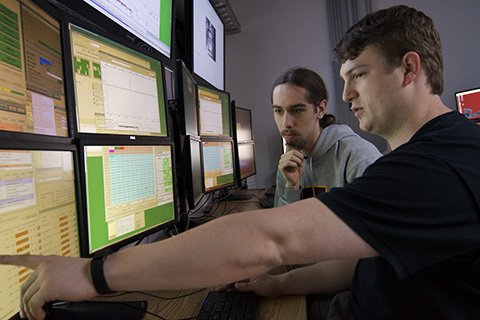 two students looking array of computer monitors