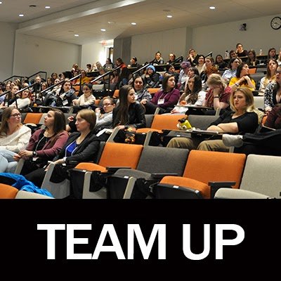 Picture of a filled lecture hall with text "TEAM UP" along the bottom