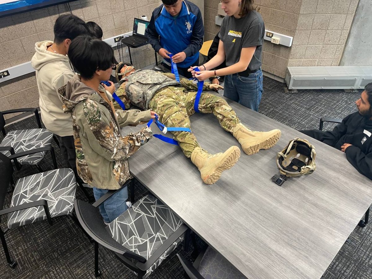 Students work with a mannikin to simulate combat injury treatment