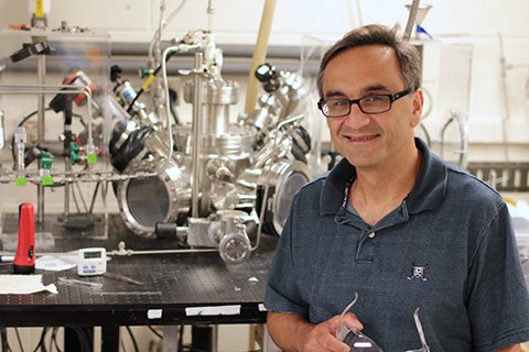 Eray Aydil posing next to equipment in his lab