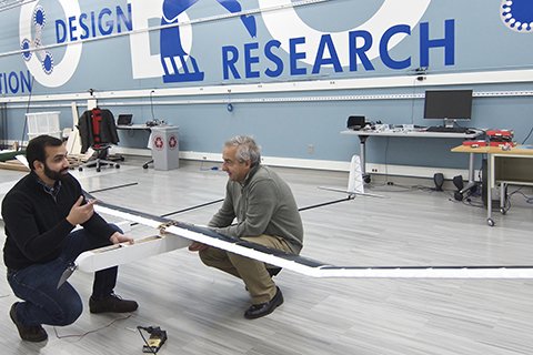 CSE researchers talk while holding parts of a solar-powered UAV