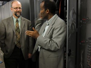 two men standing by the machines of the University of Minnesota Supercomputing Institute for Advanced Computational Research