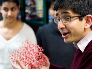 Aditya Bhan, zeolite model in hand, talks with student researchers in the lab