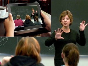 Professor teaching while student watches her on handheld device