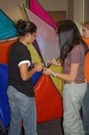 students lace together boldly colored equilateral triangles of kite fabric
