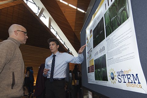 A student presents research to a visitor at the North Star STEM Alliance Kickoff