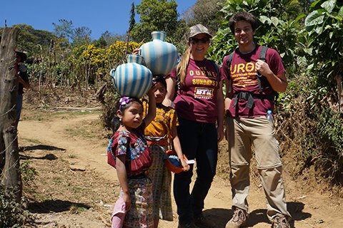 Two EWB students abroad with two native children