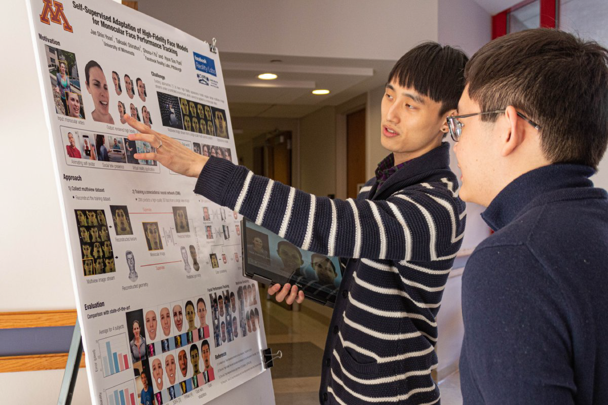 Grad student presenting poster to other students