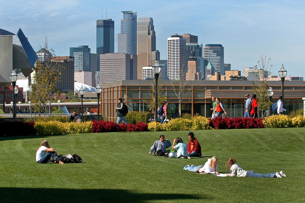 Students relaxing on the University of Minnesota campus, with the skyline in the background.