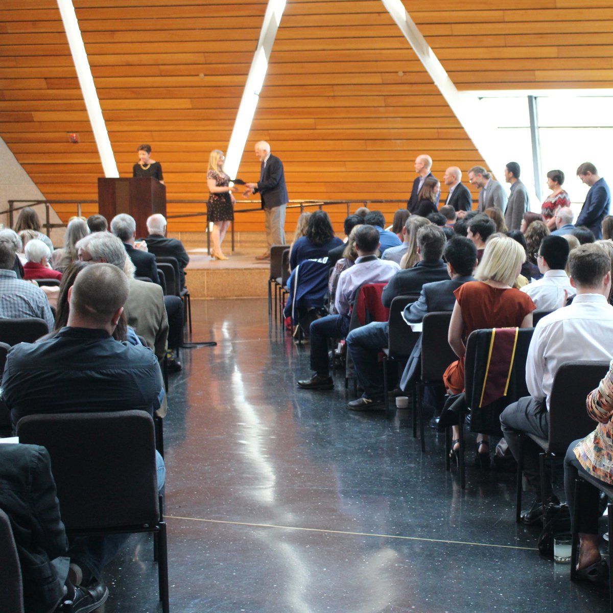 Photo of BME's undergraduate commencement reception; shows a student on stage with a faculty member, in front of an audience