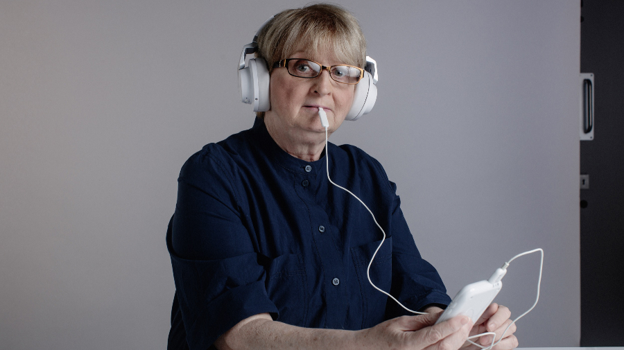 Patient wearing a headset and holding a device that inserts into their mouth