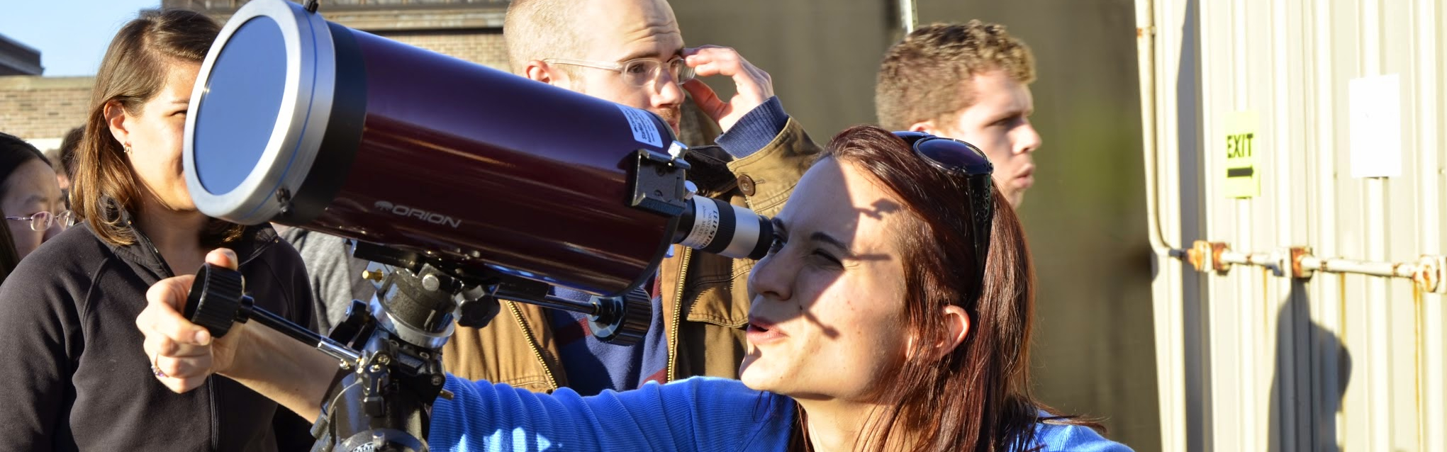 A person looks through the telescope at a Universe in the Park event.