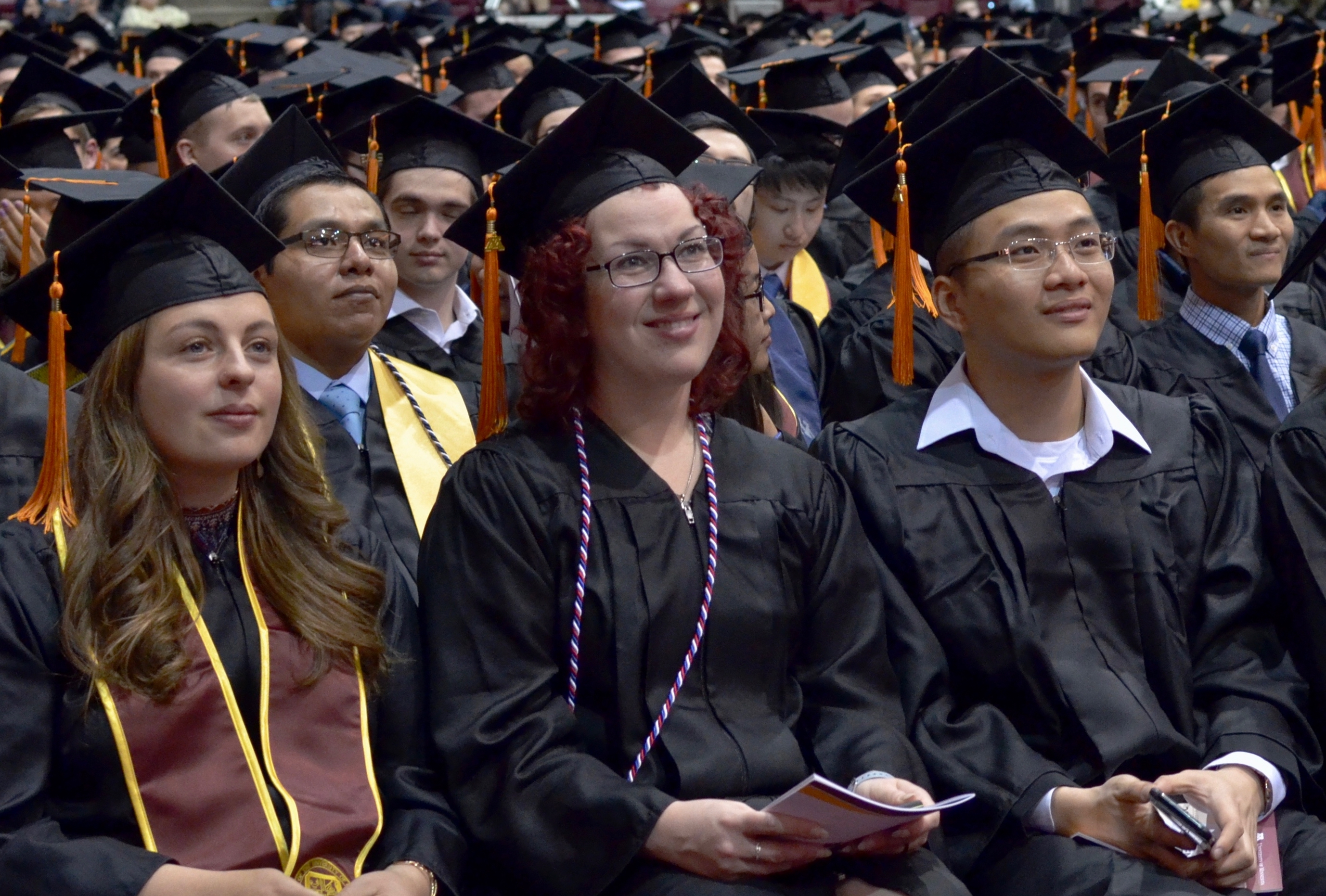 Undergradaute students in cap and gown sitting at commencement